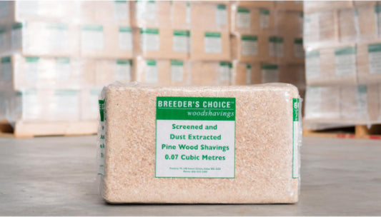 Package of Breeder's Choice wood shavings with a label on a wooden surface.